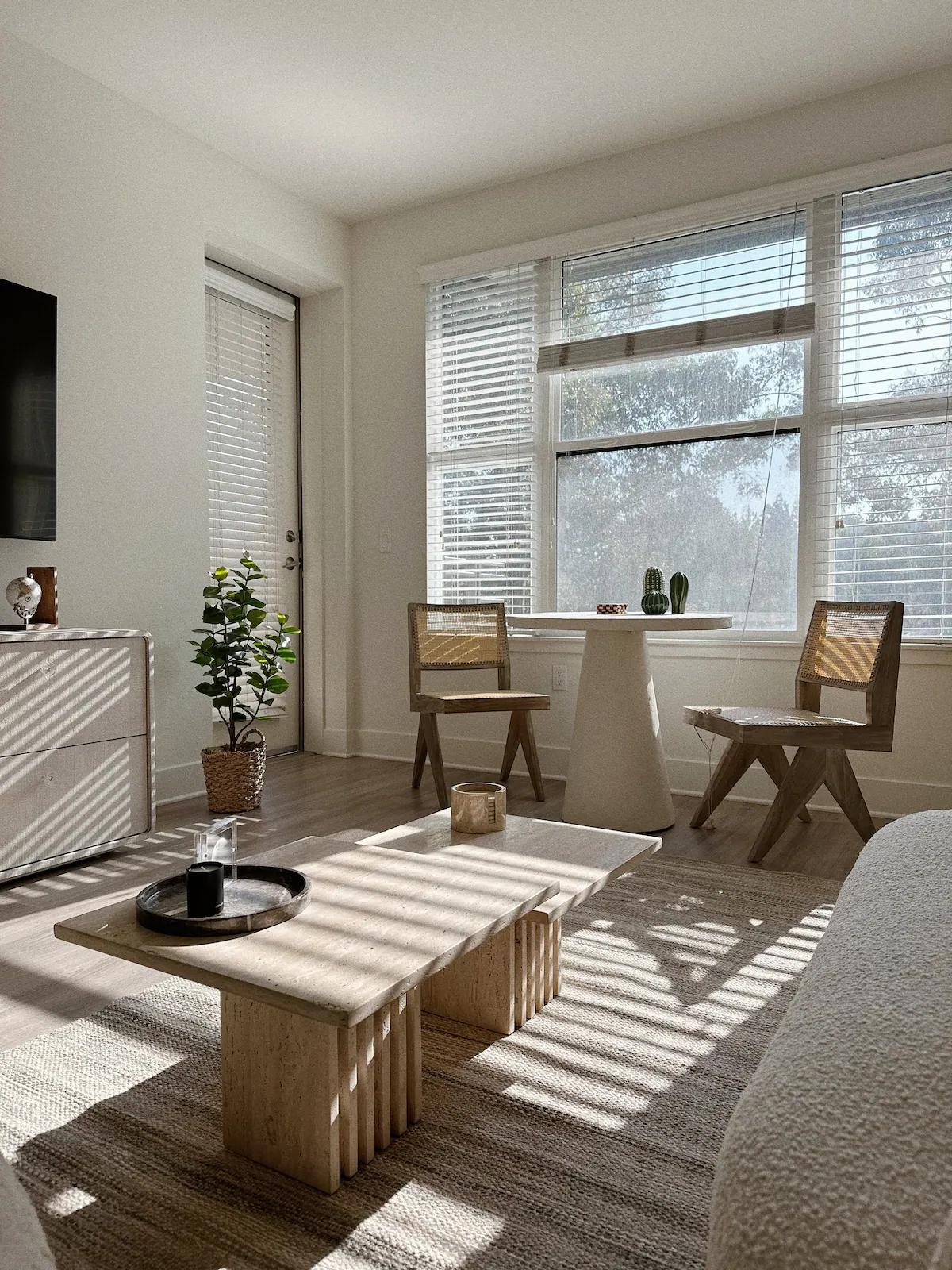 Detail of a staged rental living area with morning sunlight casting striped shadows across a rug and coffee table